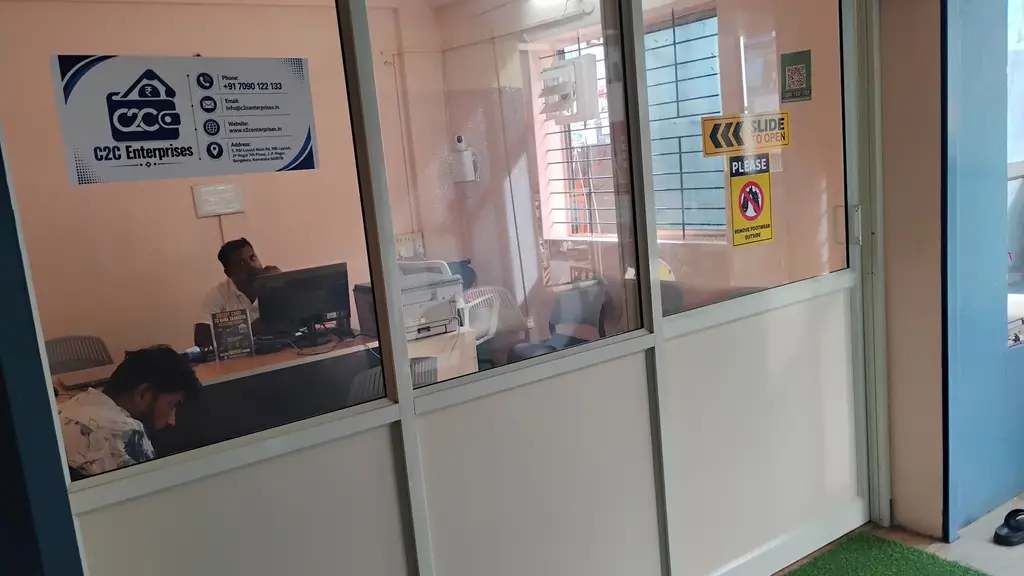 Glass-fronted C2C Enterprises office in RBI Layout, JP Nagar 7th Phase, with staff at the counter